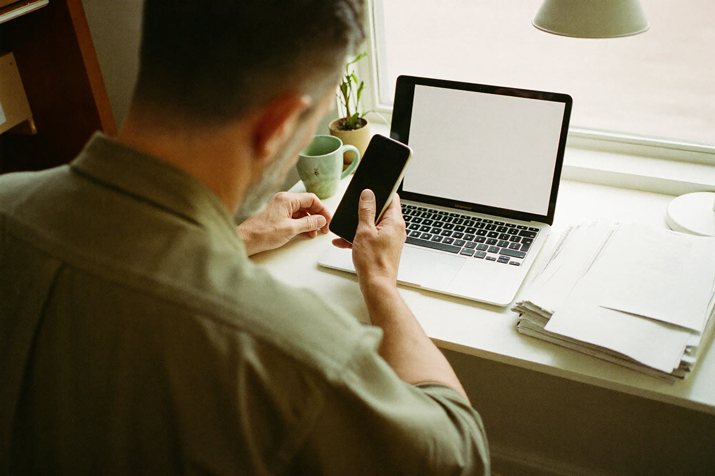 A business owner at his desk reading a new enquiry on his phone.